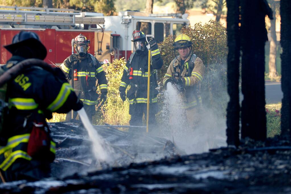 Rancho Adobe firefighter Dylan Foster, right, sprays down smoldering debris from a fire that occured in an vacant home on Magnolia Avenue, in Santa Rosa, California, on Tuesday, May 2, 2017. (Alvin Jornada / The Press Democrat)