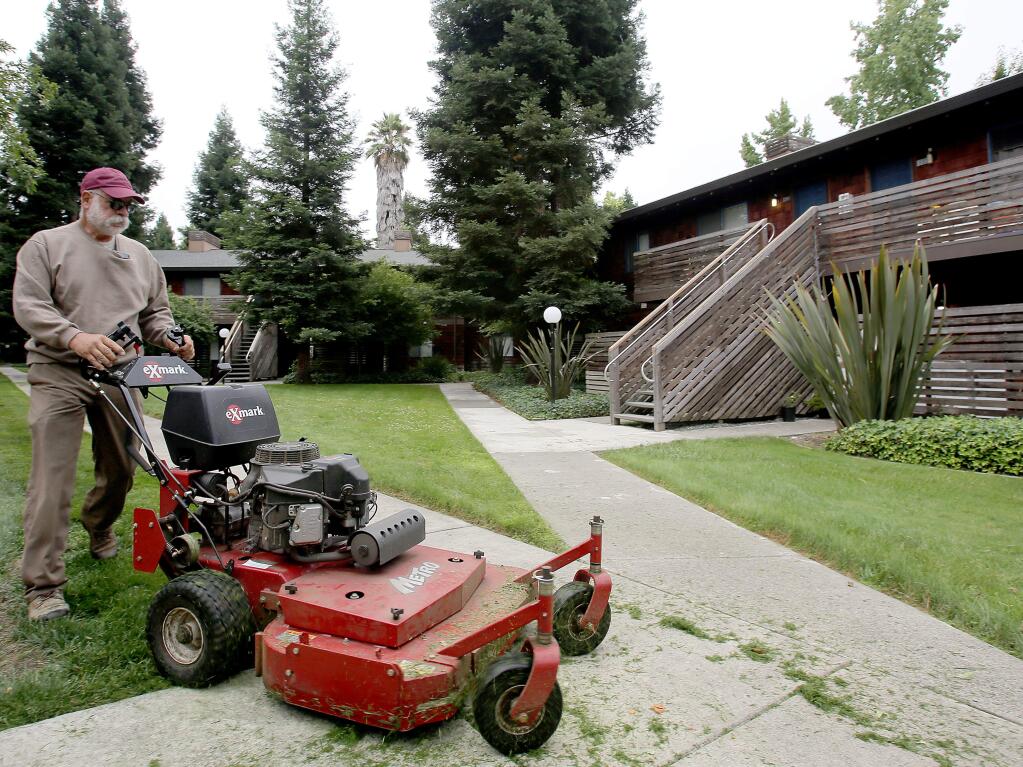 Mike Ferreira, owner of Santa Rosa Landscape, mows the lawns at Coddingtown Mall Apartments, Thursday, July 25, 2013. (Crista Jeremiason / The Press Democrat)