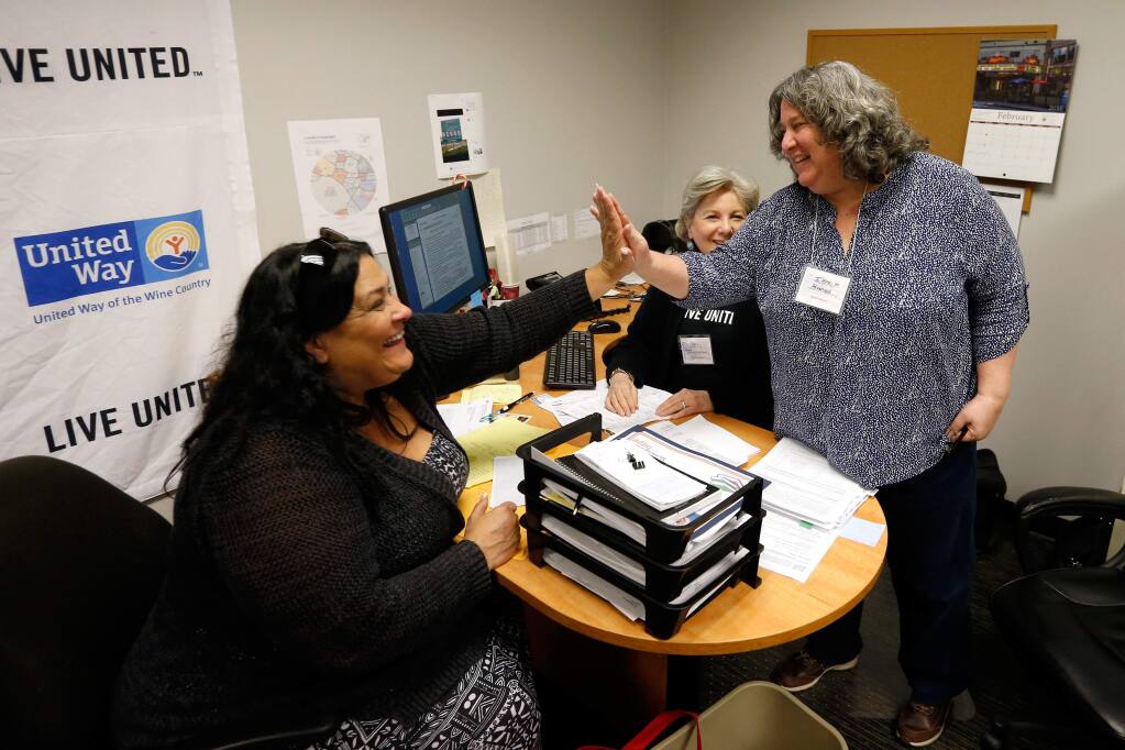An overjoyed Darlene Klaiber, left, high-fives site coordinator Ilene Moran, right, and volunteer Patty Johnston after they told Klaiber that she is receiving a refund instead of owing $1700 as Klaiber expected before coming to the Earn It, Keep It, Save It tax preparation program at the United Way office in Santa Rosa, California on Wednesday, March 30, 2016. (Alvin Jornada / The Press Democrat)
