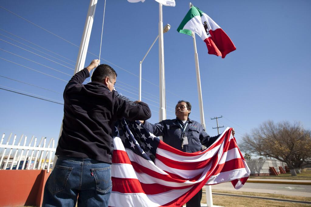 Workers raise a U.S. flag at a business in Juarez, Mexico. The United States is seeking to renegotiate the North?American Free Trade Agreement, which governs trade between the United States, Mexico and Canada. (IVAN PIERRA AGUIRRE / Associated Press, 2013)
