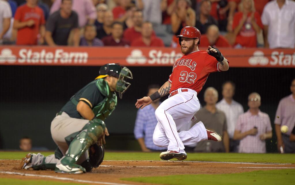Los Angeles Angels' Josh Hamilton, right, scores on a single by Erick Aybar as Oakland Athletics catcher Geovany Soto takes a late throw during the second inning of a baseball game, Thursday, Aug. 28, 2014, in Anaheim, Calif. (AP Photo/Mark J. Terrill)
