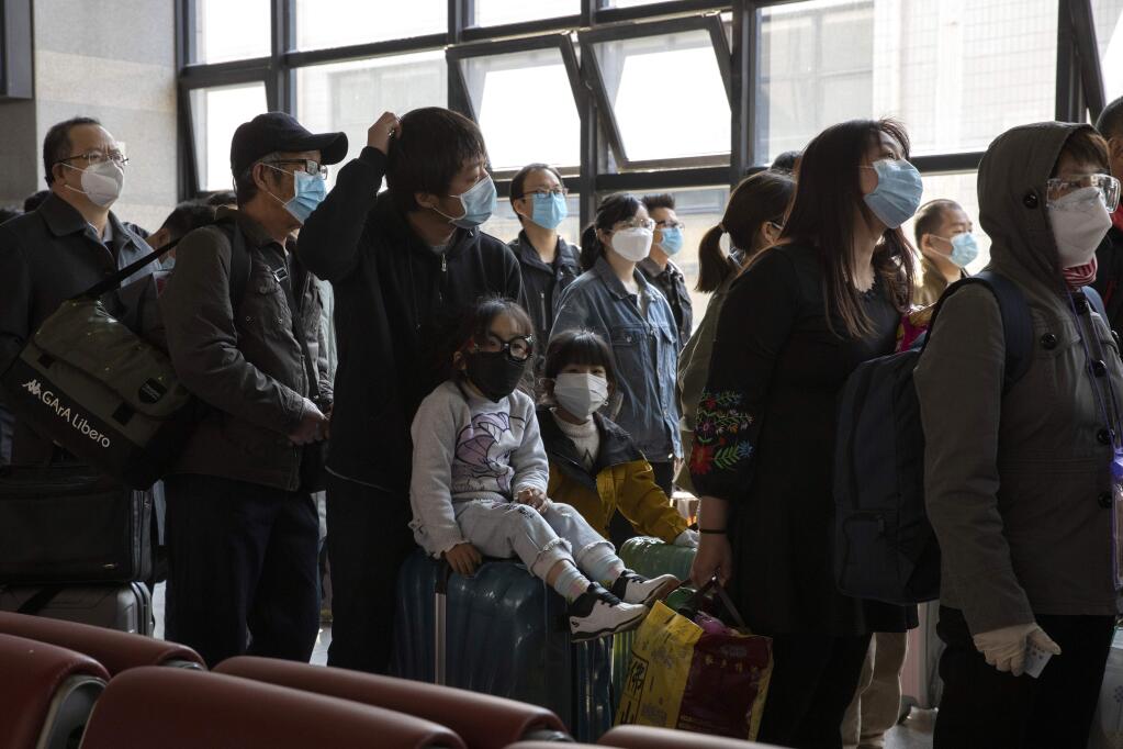 Travelers wearing face masks to help curb the spread of the coronavirus line up for their train at the station in Beijing on Sunday, March 29, 2020. As the coronavirus epicenter has shifted westward, the situation has calmed in China, with falling death rates and most new cases coming from abroad, restrictions on travel have been slowly lifted. (AP Photo/Ng Han Guan)