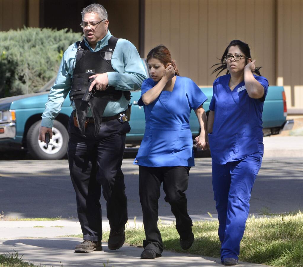 Medical personnel are evacuated by a Fresno Police officer at the scene of a shooting at a medical clinic Tuesday, March 31, 2015, in Fresno, Calif. A man and a woman were found dead after a shooting at the clinic in downtown Fresno, police in central California said. (AP Photo/The Fresno Bee, John Walker)