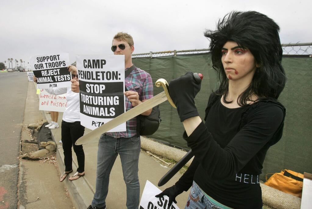 FILE - In this Aug. 12, 2009 file photo, Nasim Aghdam, right, joins members of People for the Ethical for Animals, PETA, protesting at the main gate of Marine Corps base Camp Pendleton in Oceanside, Calif., against the Marine's killings of pigs in a military exercise. Northern California authorities say the woman, who shot and wounded three people at YouTube headquarters in April 2018, died of a self-inflicted gunshot to the heart. (Charlie Neuman/The San Diego Union-Tribune via AP, file)