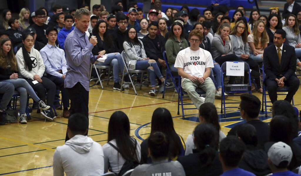 Golden State Warriors coach Steve Kerr, left, speaks to Newark Memorial High School students on Monday, March 12, 2018, in Newark, Calif. Kerr joined Rep. Ro Khanna, D-Calif., seated at right, and Matt Deitsch, 20, wearing 'Stop Gun Violence' shirt, in a town hall style conversation on gun violence in America. Deitsch's younger brother and sister stayed locked in closets during last month's shooting at Marjory Stoneman Douglas High School in Parkland, Florida. (AP Photo/Ben Margot)