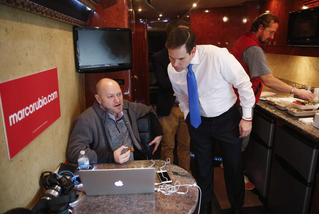 Republican presidential candidate, Sen. Marco Rubio, R-Fla. talks with senior adviser Todd Harris on his bus in Kissimmee, Fla., Tuesday, March 8, 2016. (AP Photo/Paul Sancya)