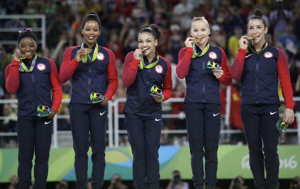 FILE - In this Aug. 9, 2016 file photo, U.S. gymnasts, from left, Simone Biles, Gabrielle Douglas, Lauren Hernandez, Madison Kocian and Aly Raisman hold their gold medals during the medal ceremony for the artistic gymnastics women's team at the 2016 Summer Olympics in Rio de Janeiro, Brazil. MTV said Thursday, Aug. 25, that Biles, Raisman, Douglas, Hernandez and Kocian along with swimmer Michael Phelps, will present awards at Sunday's MTV Video Music Awards in New York. (AP Photo/Julio Cortez, File)