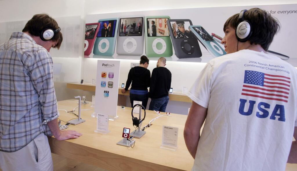 In this Oct. 19, 2007 file photo, customers try out the Apple iPod Nano at an Apple store in Palo Alto, Calif. (AP Photo/Paul Sakuma, File)