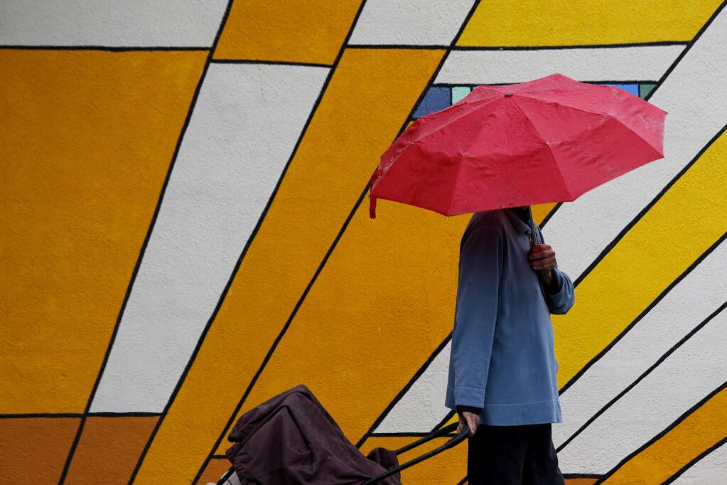 A woman who wished only to be identified as Princess tries to stay dry under an umbrella in Santa Rosa, on Thursday, July 9, 2015. (BETH SCHLANKER/ The Press Democrat)