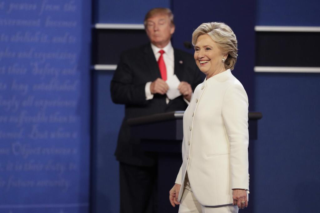 Democratic presidential nominee Hillary Clinton walks toward the audience as Republican presidential nominee Donald Trump stands behind his podium after the third presidential debate at UNLV in Las Vegas, Wednesday, Oct. 19, 2016. (AP Photo/John Locher)