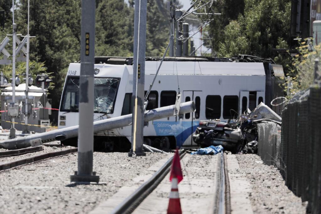Two people are dead after a car and a light rail collided near Lincoln and Auzerais avenues in San Jose, Calif., on Sunday, July 8, 2018. The northbound train of the Santa Clara Valley Transportation Authority (VTA) went off the track after it hit the car with at least two individuals inside and pulled the car along the track for several meters. Police said the driver was trying to drive around the railway crossing arms, which were lowered down and functioning normally. (Randy Vazquez/East Bay Times via AP)