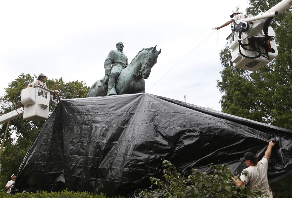 City workers drape a tarp over the statue of Confederate General Robert E. Lee in Emancipation park in Charlottesville, Va., Wednesday, Aug. 23, 2017. The move to cover the statues is intended to symbolize the city's mourning for Heather Heyer, killed while protesting a white nationalist rally earlier this month. (AP Photo/Steve Helber)