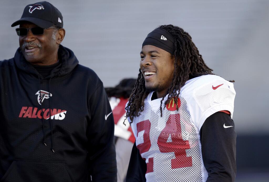 Atlanta Falcons running back Devonta Freeman (24) smiles as he talks with assistant coach Bobby Turner during a practice at the University of Washington Wednesday, Oct. 12, 2016, in Seattle. Rather than head home, the team traveled directly to Seattle after a football game Sunday in Denver, ahead of playing the Seattle Seahawks this coming Sunday in Seattle. (AP Photo/Elaine Thompson)