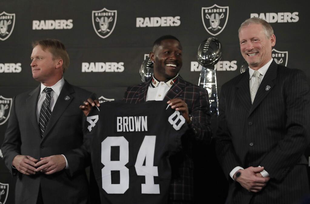 Oakland Raiders wide receiver Antonio Brown, center, holds his jersey next to coach Jon Gruden, left, and general manager Mike Mayock during a news conference Wednesday, March 13, 2019, in Alameda. (AP Photo/Ben Margot)