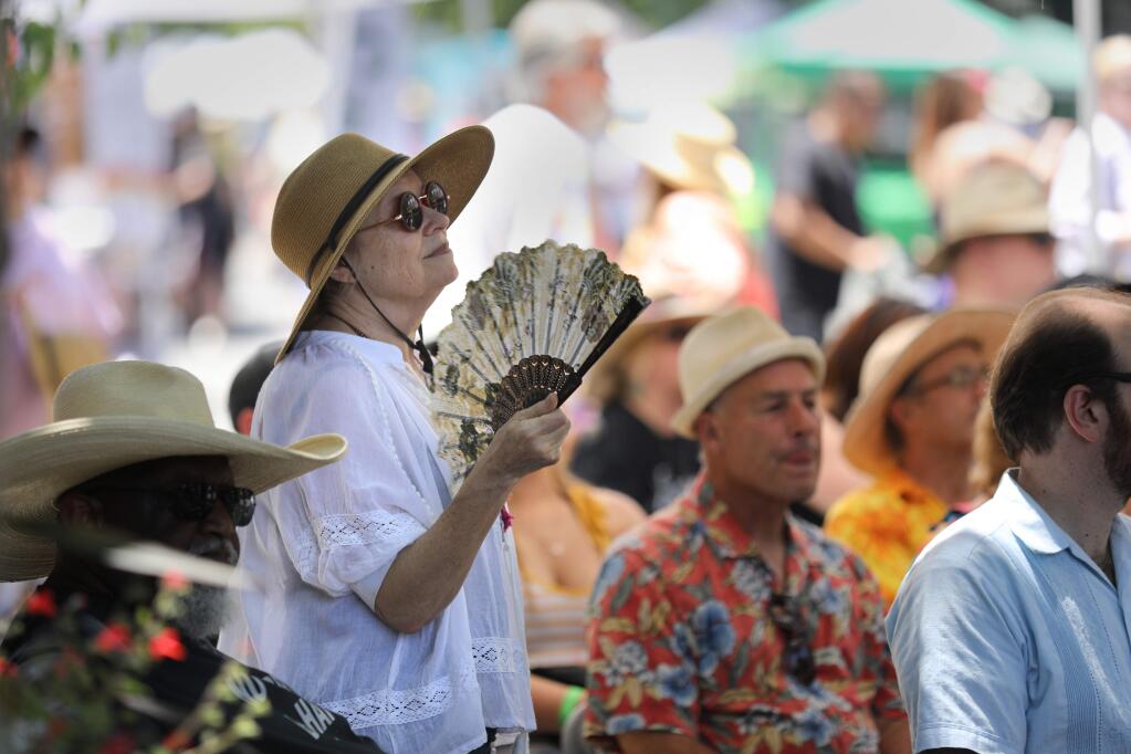 Susan Price fans herself to stay cool during the Railroad Square Music Festival in Santa Rosa, California on Sunday, June 9, 2019. (BETH SCHLANKER/The Press Democrat)