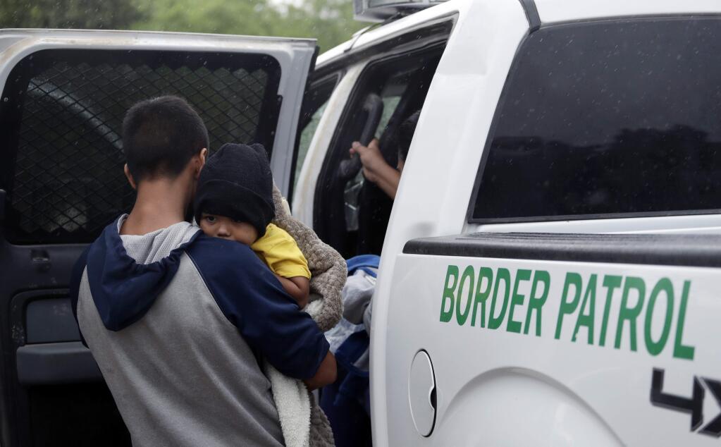FILE - In this March 14, 2019, file photo, families who crossed the nearby U.S.-Mexico border near McAllen, Texas are placed in a Border Patrol vehicle. (AP Photo/Eric Gay, File)