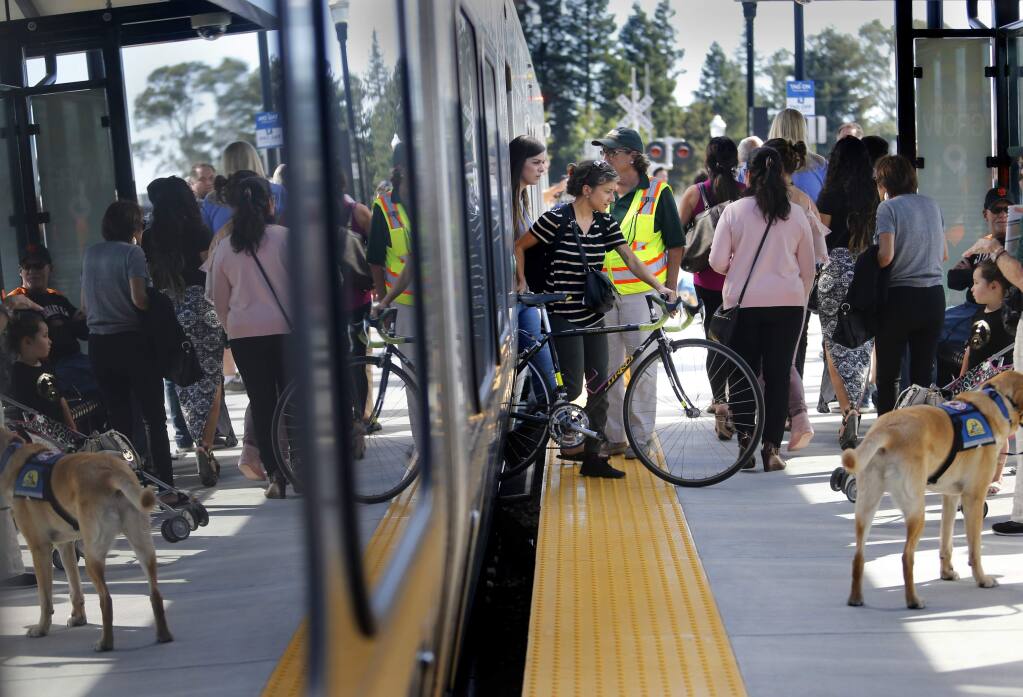 Lupita C.A. maneuvers her bicycle as she disembarks from the SMART train on Friday, Sept. 29, 2017 in Santa Rosa, California. (BETH SCHLANKER/ PD)