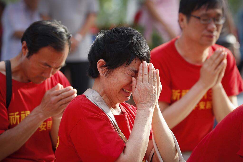 Chinese family members of passengers on board the missing Malaysia Airlines Flight 370 cries as they pray at a temple in Kuala Lumpur, Malaysia, Sunday, March 1, 2015. (AP Photo/Vincent Thian)