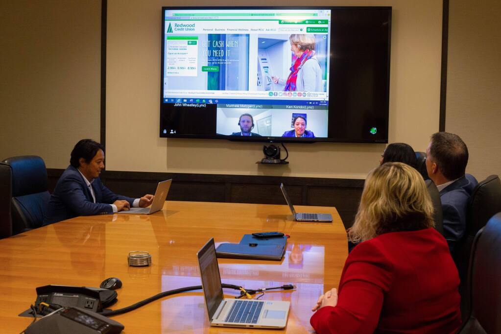Redwood Credit Union programming manager Ken Kondo, seated at left, and his colleagues demonstrate the bank's video conferencing abilities which also allows screen sharing with employees telecommuting from their homes, amidst the COVID-19 coronavirus pandemic, at the RCU main office in Santa Rosa, California, on Thursday, March 12, 2020. (Alvin Jornada / The Press Democrat)