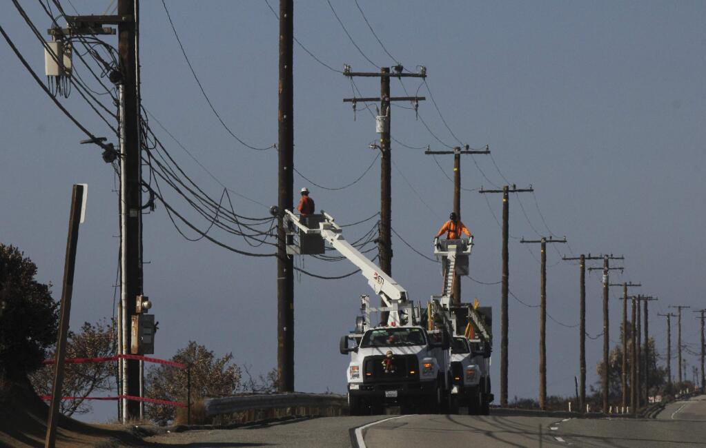 FILE - In this Nov. 25, 2018 file photo Utility crews repair overhead lines along Pacific Coast Highway just west of Malibu, Calif., where the Woolsey Fire burned down from the Santa Monica Mountains to the water's edge at Leo Carrillo State Beach. Southern California Edison announced in its quarterly earnings report that its equipment probably caused the November 2018 Woolsey Fire that raged from north of Los Angeles through Malibu to the sea, killing three people and burning more than 1,600 homes and other buildings. (AP Photo/John Antczak,File)