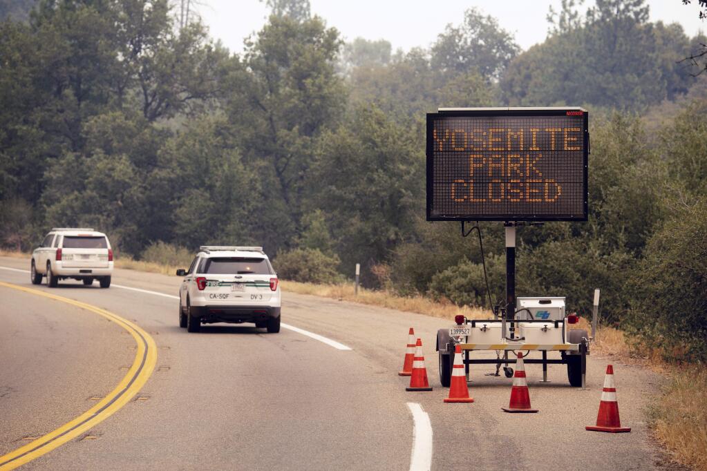 FILE - In this July 25, 2018 file photo, a sign on Highway 41 announces the closure of Yosemite National Park near Oakhurst, Calif. Yosemite National Park could reopen its scenic valley and other areas Monday, Aug. 6, 2018, if conditions improve after a 12-day closure due to nearby wildfires. The park‚Äôs iconic cliffs have been shrouded in so much smoke that the air quality in Yosemite is currently worse than Beijing. (AP Photo/Noah Berger, File)