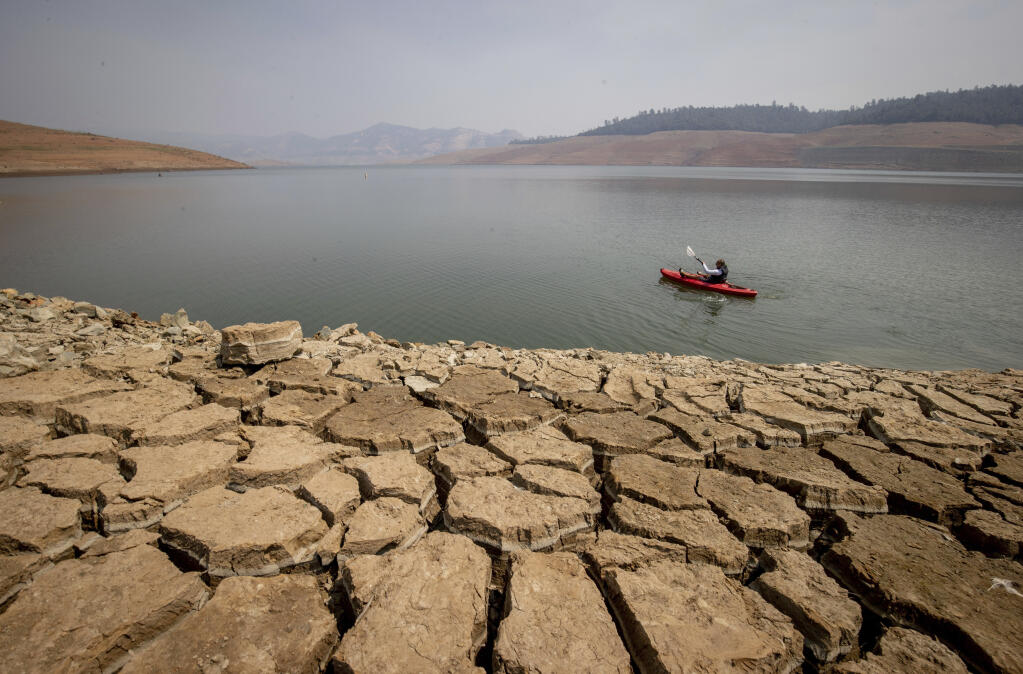 FILE — In this Aug. 22, 2021, file photo a kayaker fishes in Lake Oroville as water levels remain low due to continuing drought conditions in Oroville, Calif. California's reservoirs are so low from a historic drought that regulators warned Thursday, Sept. 30, 2021, it's possible the state's water agencies could get nothing from them next year, a frightening possibility that could force mandatory restrictions for residents. (AP Photo/Ethan Swope, File)