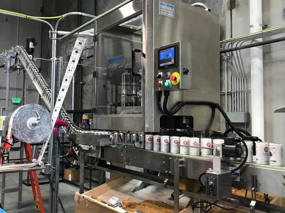 An applicator puts printed shrink-sleeve beer labels onto blank aluminum cans, which are called “brites,” in a We Sleeve-It plant in Lacey, Washington, in 2018. (Facebook)