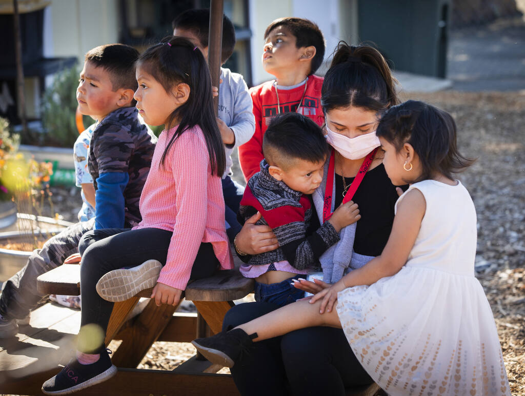 Teacher Alondra Ortega, second from right, comforts Leonardo Ramirez, 4, while the other students seek safety on a table while playing “hot lava” at the North Bay Children’s Center in Healdsburg on Tuesday, March 8, 2022.  (John Burgess/The Press Democrat)