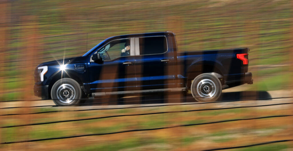 A  F-150 Lightning Pro Ford electric vehicle is driven on a service road at Dutton Ranch in Sebastopol, Tuesday, Jan. 25, 2022. Ford launched a pilot program with area growers, Bevill Vineyard Management, Vino Farms in Healdsburg and Dutton Ranch, to use a small fleet of electric vehicles including the  F-150 Lightning Pro and  E-Transit cargo vans for vineyard operations. (Kent Porter / The Press Democrat) 2022