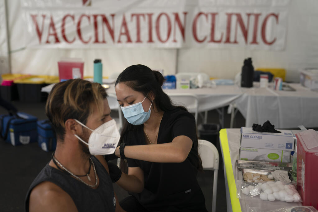 Registered nurse, Noleen Nobleza, center, inoculates Julio Quinones with the COVID-19 vaccine at a clinic set up in the parking lot of CalOptima Saturday, Aug. 28, 2021, in Orange, Calif. (AP Photo/Jae C. Hong)