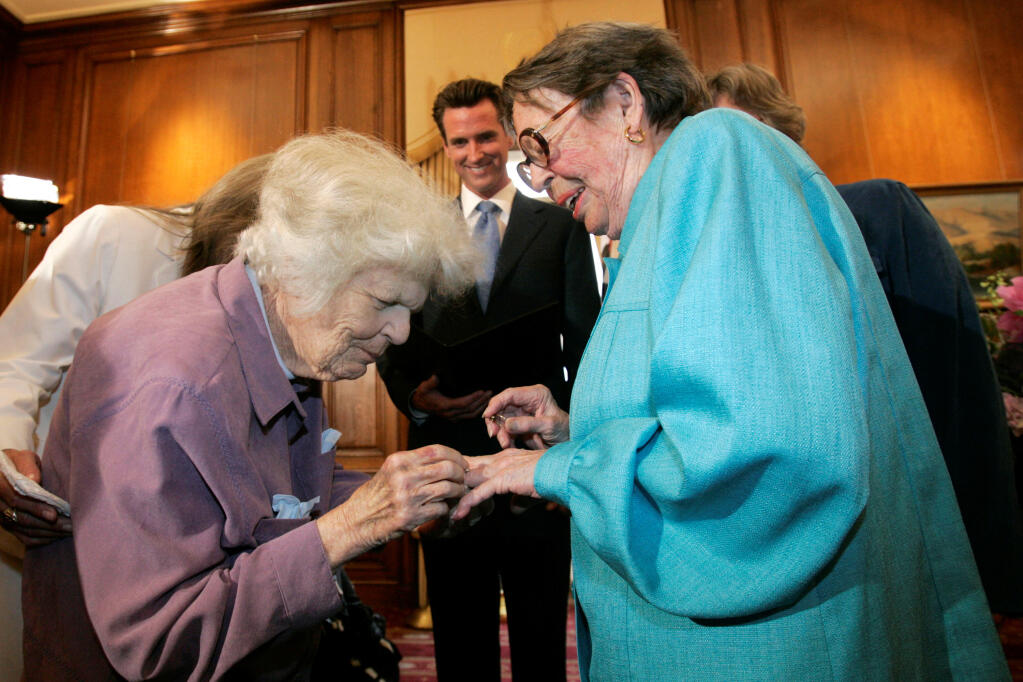 FILE - In this June 16, 2008, file photo, Del Martin, left, places a ring on her partner Phyllis Lyon, right, during their wedding ceremony officiated by then-San Francisco Mayor Gavin Newsom, center, at City Hall in San Francisco.  (AP Photo/Marcio Jose Sanchez, File)