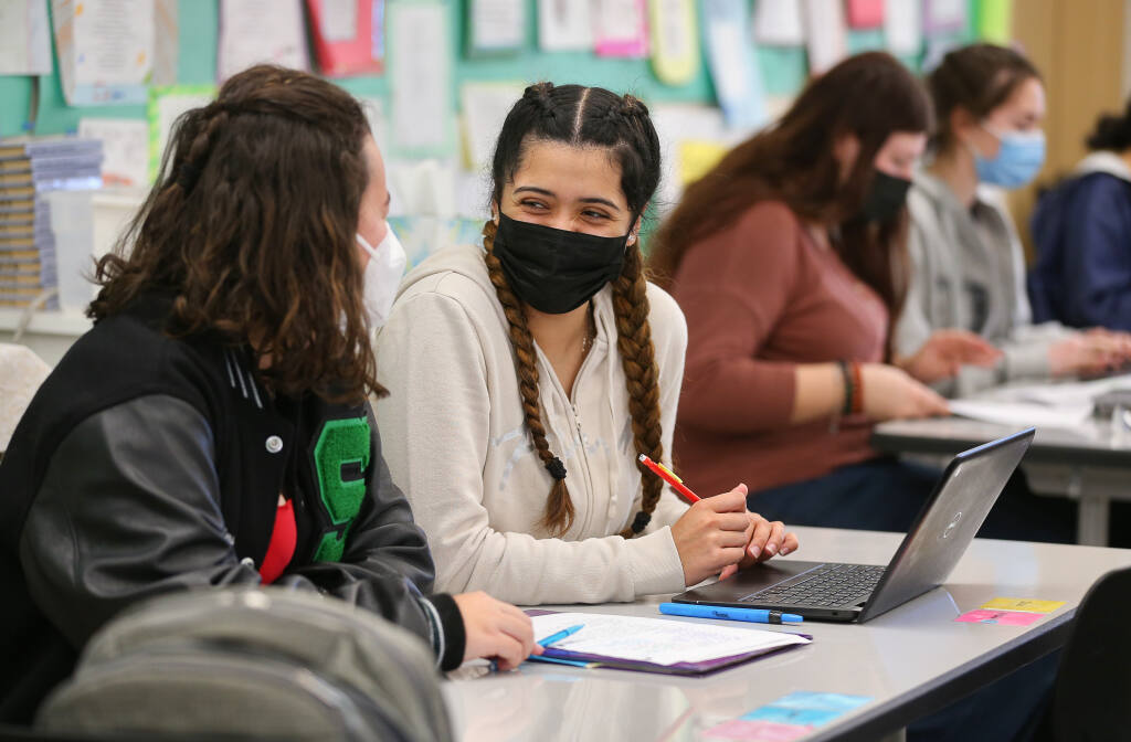 Sonoma Valley High School senior Heidi Zaragoza, right, talks with classmate Ella Perkins in their honors English class in Sonoma on Friday, Feb. 11, 2022.  With the help of a school college counselor and a mentor from 10,000 Degrees, Zaragoza completed her FAFSA application and applied to several colleges.  (Christopher Chung / The Press Democrat)