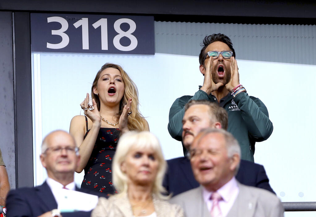 Wrexham co-owner, actor Ryan Reynolds background right and his wife, Blake Lively react in the stands, prior to the FA Trophy soccer final match between Wrexham and Bromley, at Wembley Stadium, in London, Sunday May 22, 2022. (Kieran Cleeves/PA via AP)