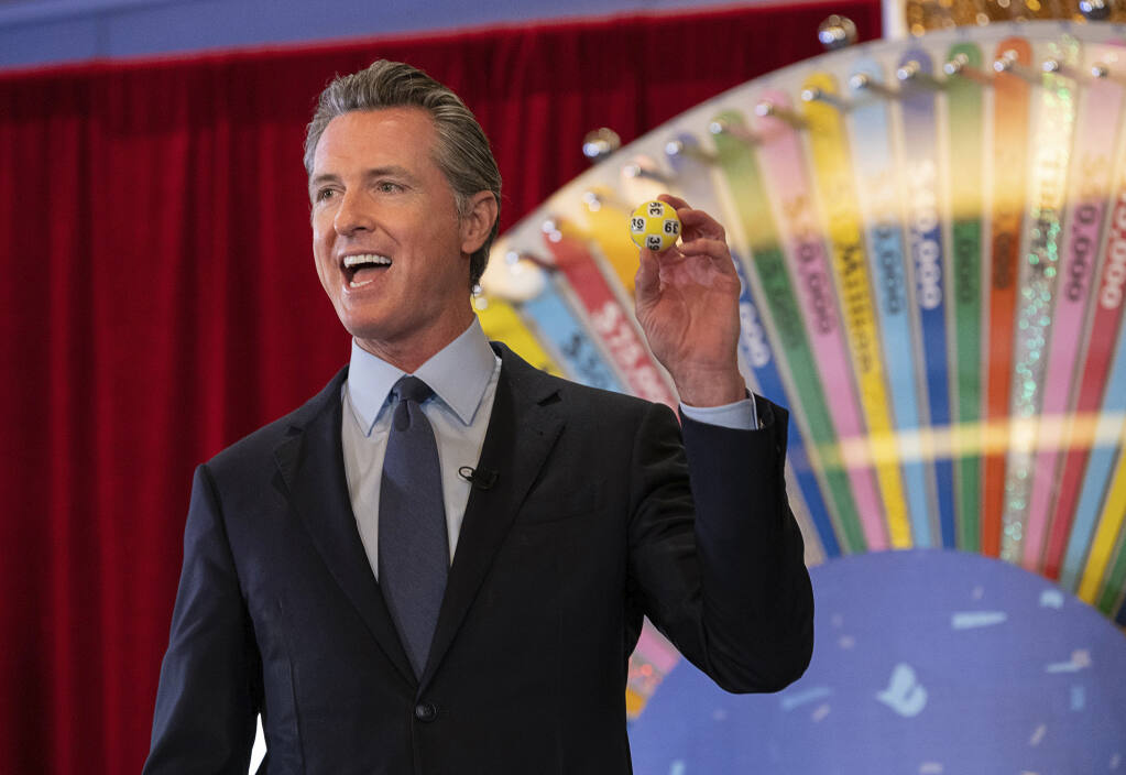 California Gov. Gavin Newsom holds up a lottery ball at the California Lottery Headquarters on Friday, June 4, 2021, in Sacramento, Calif., while drawing numbers for California’s new vaccine incentive program. It was the first in a series of drawings for $16.5 million in prize money aimed at encouraging Californians to get their shots ahead of June 15, when the state plans to lift almost all virus-related restrictions. (Paul Kitagaki Jr./The Sacramento Bee via AP)