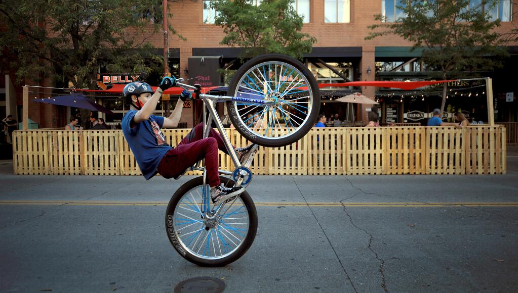 Jonah Feith, 14, of Santa Rosa performs a wheelie on Fourth Street, Friday, July 10, 2020 as he and his friends take advantage of a three-month closure from B Street to E Street. (Kent Porter / The Press Democrat)