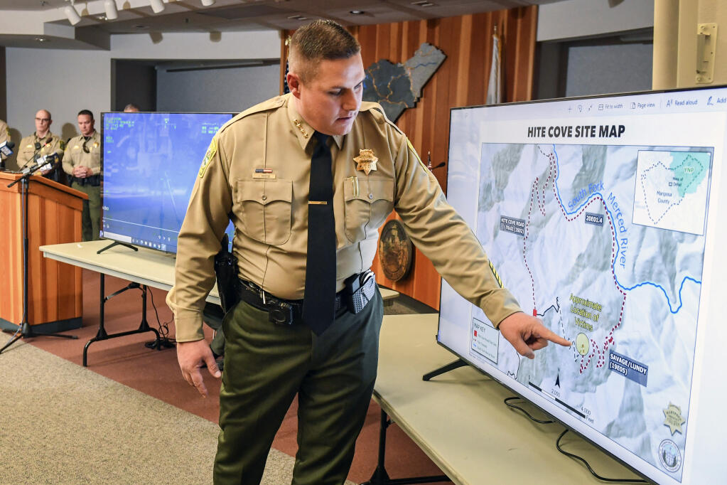 Mariposa County Sheriff Jeremy Briese points to a map to show where a missing family was found dead during a news conference in Mariposa, Calif., Thursday, Oct. 21, 2021. A Northern California sheriff says a family and their dog died of extreme heat exhaustion while hiking in a remote area in August. Sheriff Briese said that John Gerrish, his wife, Ellen Chung, their 1-year-old daughter, Miju, and their dog were walking in extreme heat before they died. Briese says their water container was empty. (Craig Kohlruss/The Fresno Bee via AP)