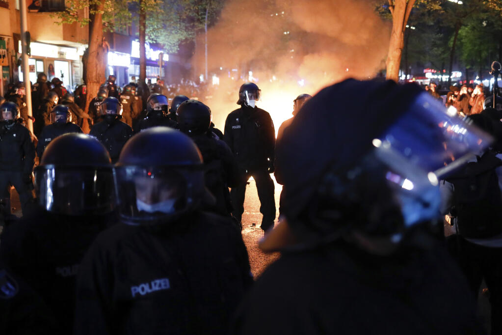 Police officers stand in front of a fire set up by demonstrators during a May Day rally in Berlin, Germany, Saturday, May 1, 2021. (AP Photo/Markus Schreiber)