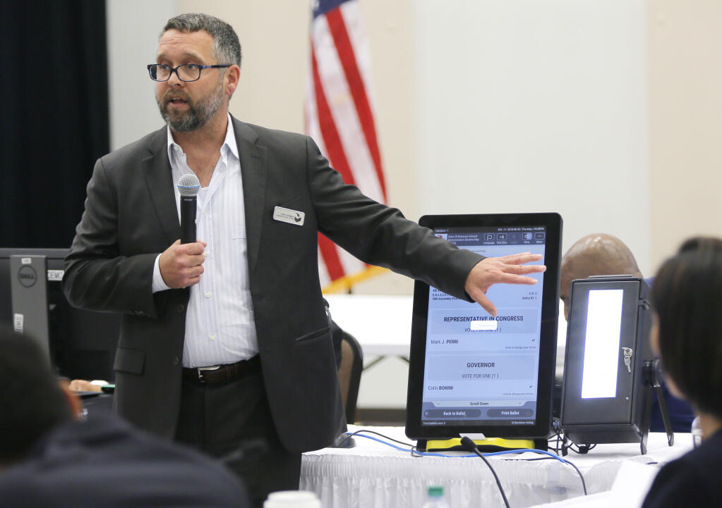 FILE - In this Aug. 30, 2018 file photo, Eric Coomer from Dominion Voting demonstrates his company's touch screen tablet that includes a paper audit trail at the second meeting of Secretary of State Brian Kemp's Secure, Accessible & Fair Elections Commission in Grovetown, Ga. Attorneys for President Donald Trumpâ€™s re-election campaign, its onetime attorney Rudy Giuliani and conservative media figures asked a judge Wednesday, Oct. 13, 2021, to dismiss a defamation lawsuit by Coomer, a former employee of Dominion Voting Systems, who argues he lost his job after being named in false charges as trying to rig the 2020 election.  (Bob Andres/Atlanta Journal-Constitution via AP, File)