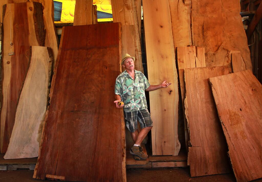 MIchael Deakin, the founder of Heritage Salvage in Petaluma, with some this slabs of redwood, bay and other hardwoods.
