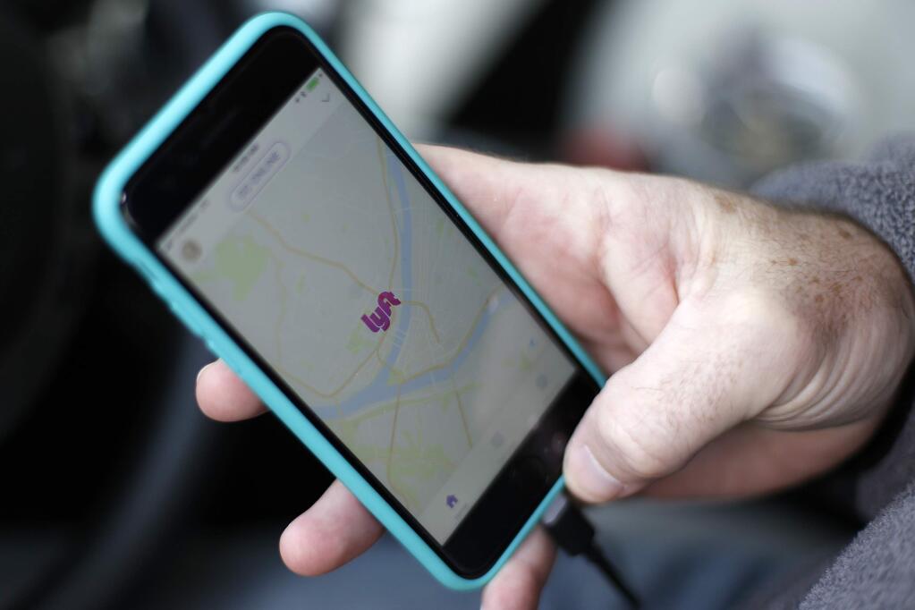 FILE- In this Jan. 31, 2018, file photo, a Lyft driver opens the Lyft app on his phone while waiting for a fare in Pittsburgh. (AP Photo/Gene J. Puskar, File)