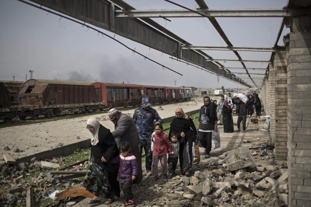 Iraqi civilians flee through a destroyed train station during fighting between Iraqi security forces and Islamic State militants, on the western side of Mosul, Iraq, Sunday, March 19, 2017. More than 750 civilians have been killed or wounded in the first month of fighting in the Iraqi offensive to retake western Mosul from the Islamic State group, front-line medics say, a number they expect to spike as Iraqi forces push into Mosul's old city. Iraqi forces have increasingly turned to airstrikes and artillery in the heavily populated urban terrain, and impoverished residents running out of food are forced to flee their homes, making dangerous journeys across front lines. (AP Photo/Felipe Dana)