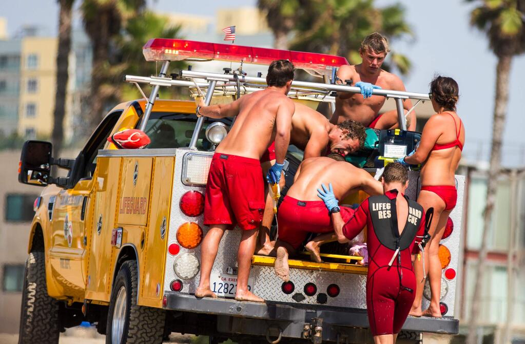 Lifeguards assist a person who was in the water and struck by lightening Sunday July 27, 2014 in Los Angeles. (AP Photo/Steve Christensen)
