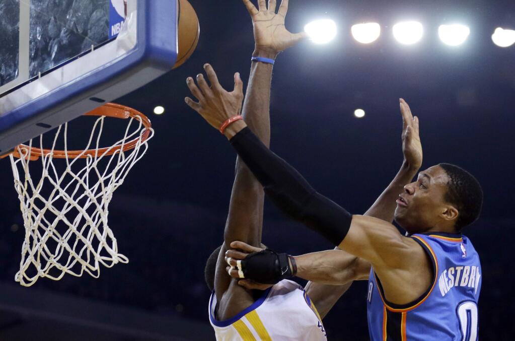 Oklahoma City Thunder guard Russell Westbrook, right, lays up a shot past Golden State Warriors' Festus Ezeli during the first half of a game Thursday, Dec. 18, 2014, in Oakland. (AP Photo/Ben Margot)