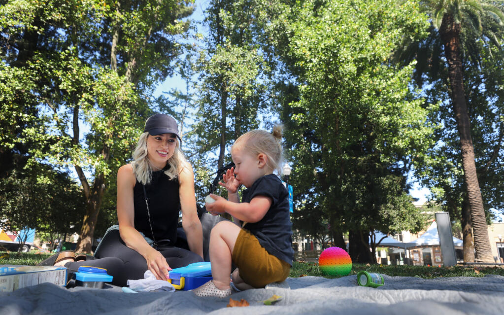 Nanny Alicia Yanos, left, spends the morning with Nikko Molden in the Healdsburg Plaza on Thursday, August 20, 2020.  Yanos noticed less people around the plaza due to the fire.(Christopher Chung/ The Press Democrat)