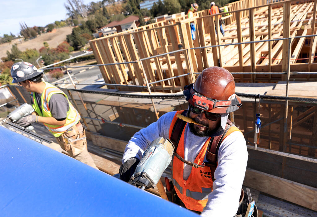 Mo Torres, right, installs siding on a Burbank Housing project, building senior affordable housing on the former Journey’s End mobile home park site, Oct. 25, 2022 in Santa Rosa.   (Kent Porter / The Press Democrat) 2022
