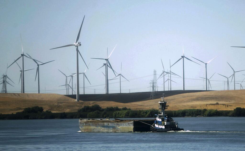 FILE - In this Sept. 23, 2013, file photo, a tugboat pushes a barge down the Sacramento River past wind turbines near Rio Vista, Calif. A contentious proposal to link oversight of California's electric grid with other western states faces a crucial test Tuesday, June 19, 2018, in a state Senate committee. (AP Photo/Rich Pedroncelli, File)