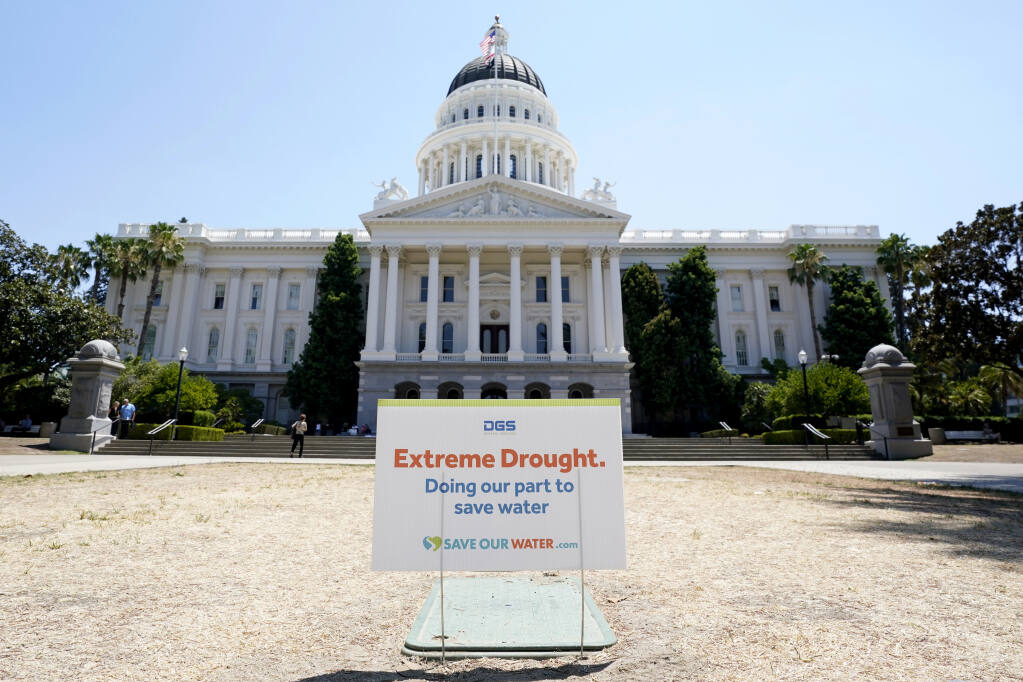 FILE - A sign about saving water is posted on browning grass outside the state Capitol in Sacramento, Calif., on Monday, July 11, 2022. California's water use dropped more than 10% in July compared to two years ago, state officials said Wednesday Sept. 7, 2022. (AP Photo/Rich Pedroncelli, File)