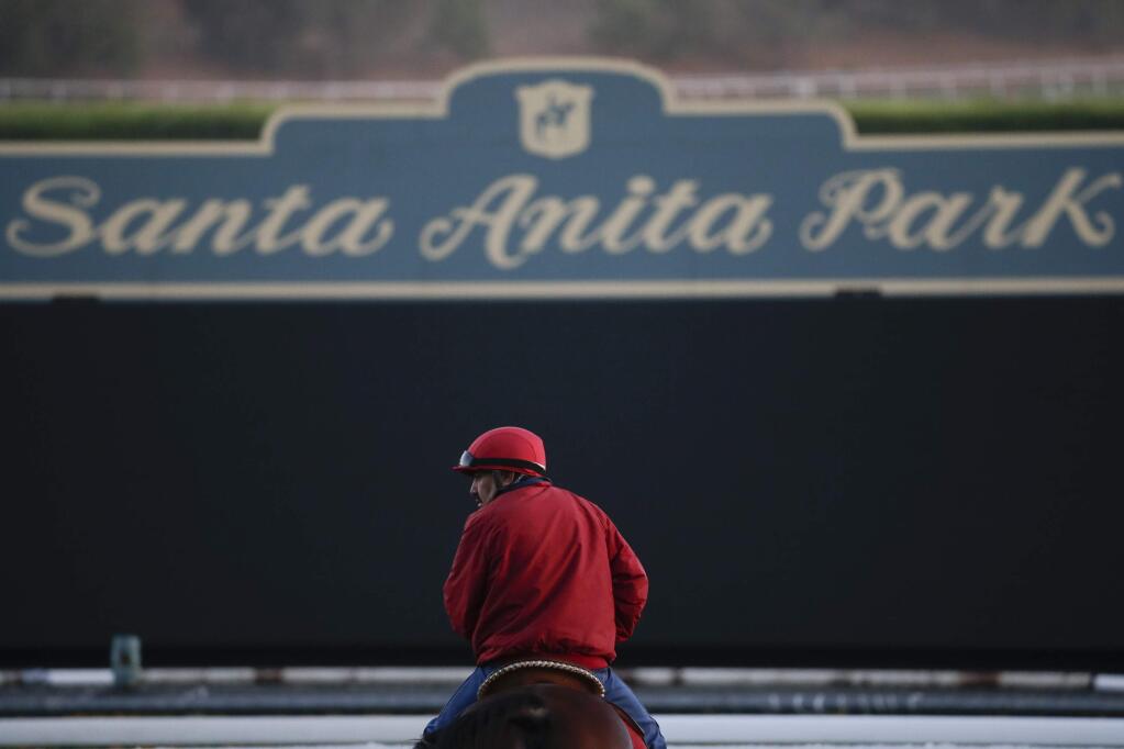 FILE - In this Oct. 29, 2014, file photo, an outrider waits by the track as horses train for the Breeders' Cup horse races at Santa Anita Park in Arcadia, Calif. (AP Photo/Jae C. Hong, File)