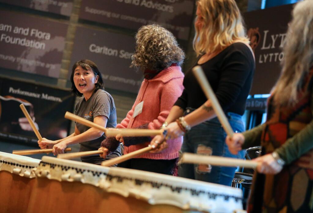 Meg Mizutani, teaching artist and Taiko drummer, left, teaches volunteers how to drum during a demonstration at the Sonoma County Arts Education Framework breakfast event at the Luther Burbank Center for the Arts in Santa Rosa on Thursday, Dec. 12, 2019. (Christopher Chung/ The Press Democrat)