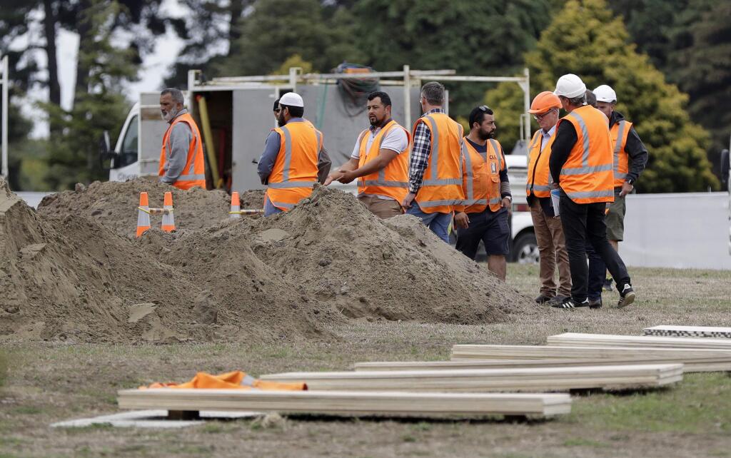 Workers watch as graves are prepared at a Muslim cemetery following the Friday mass shootings at two mosques in Christchurch, New Zealand, Sunday March 17, 2019. The live-streamed attack by an immigrant-hating white nationalist killed dozens of people as they gathered for weekly prayers in Christchurch on Friday March 15. (AP Photo/Mark Baker)